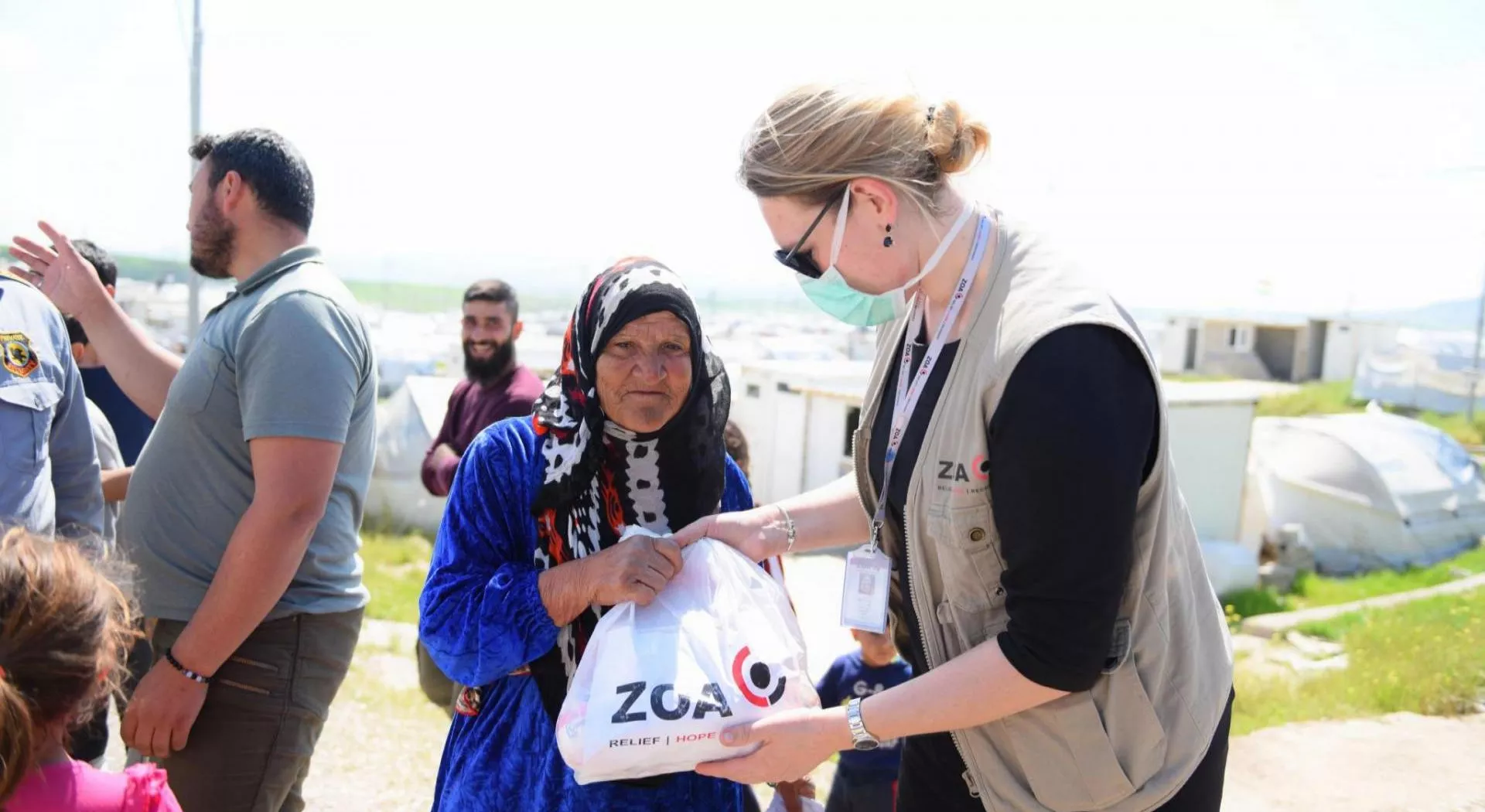 A ZOA worker handing out a bag with essential needs to a woman
