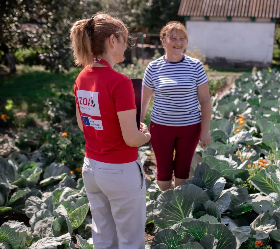 A ZOA employee standing in a field with a project participant