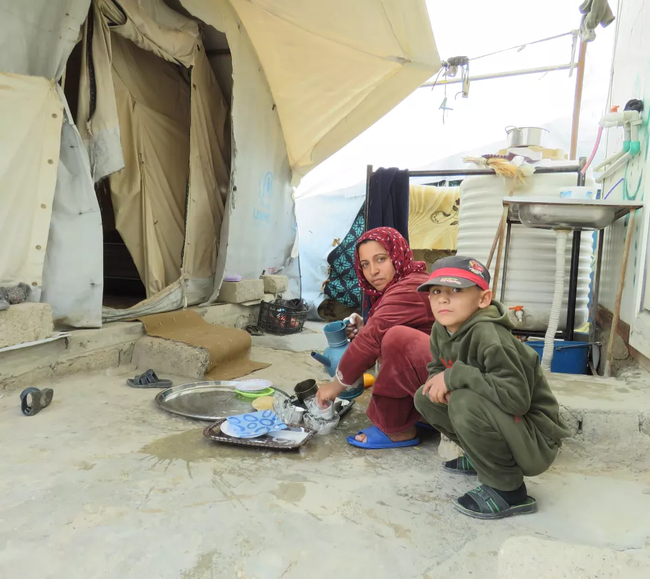 Woman with children in front of a leaky tent in Bardarash