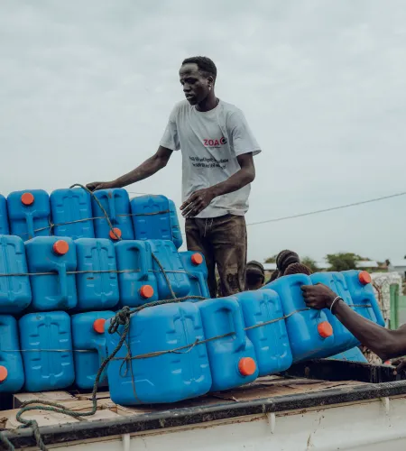 Een ZOA medewerker deelt jerrycans uit
