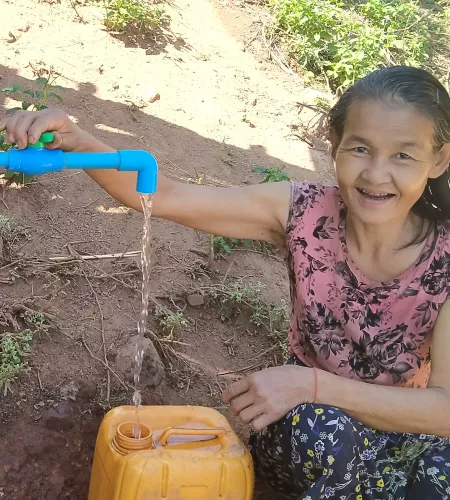 Vrouw tapt water uit een door ZOA aangelegde watervoorziening